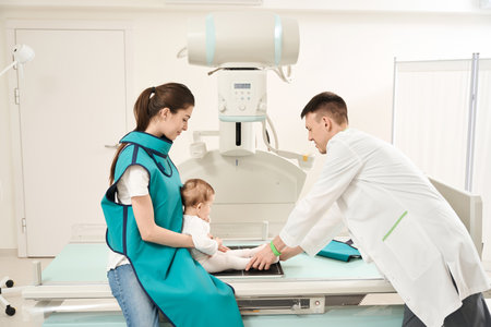 Qualified radiographer preparing toddler for x-ray of lower extremityの写真素材