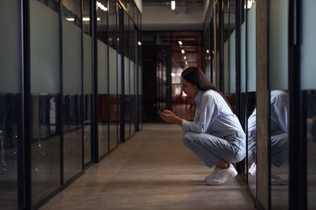 Company employee reading something on smartphone screen in office corridorの写真素材