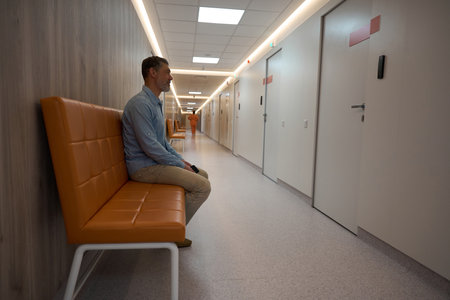 Adult male waiting on couch outside doctor office in hospitalの写真素材