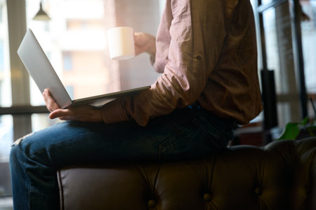 Freelancer using his portable computer over cup of coffeeの写真素材