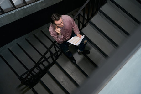 Employee communicating on mobile phone on staircase in office building