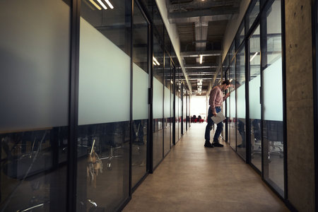 Despondent company employee standing alone in office corridorの写真素材