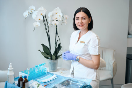 Happy doctor sitting in front of desk with medical stuffの写真素材