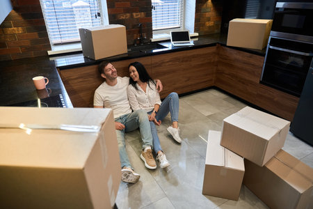 Young caucasian couple sitting on the floor in the kitchenの写真素材