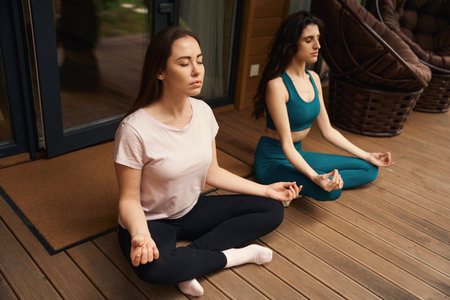 Young women meditating on floor in the backyardの写真素材
