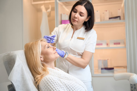 Beautician performing antiwrinkle injection on client faceの写真素材
