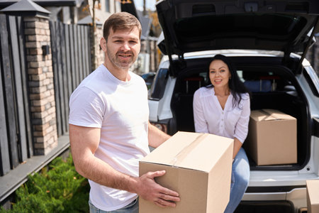 Woman sitting in car trunk next to box