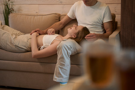 Lady lies on man lap on sofa in roomの写真素材