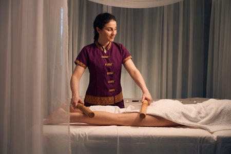 Spa therapist massaging patient lower limb during Creole massotherapy sessionの写真素材
