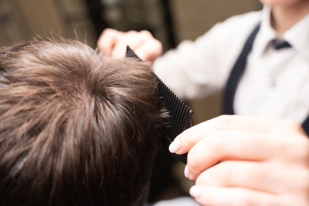 Master hairdresser cuts a client under a comb with scissorsの写真素材