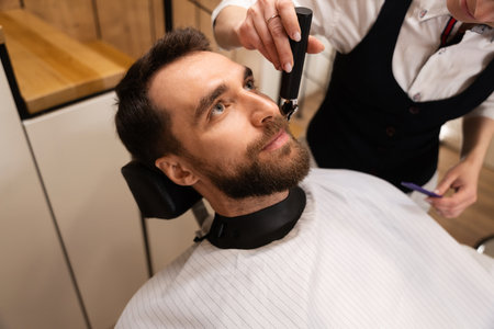 Barber cuts the beard and mustache to the clientの写真素材