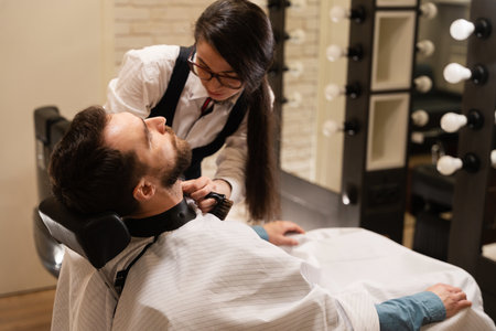 Female in glasses cuts a beard to a manの写真素材