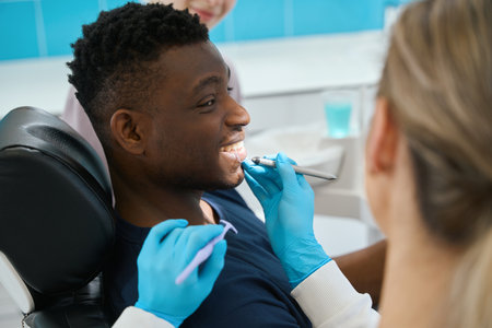Smiling African American guy looking at female stomatologist