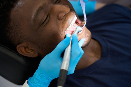 Female dentist looking at mouth mirror and working with dental drillの写真素材