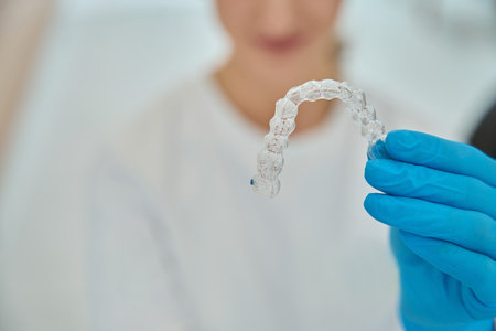 Stomatologist holding invisible removable aligners for teeth straightening