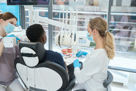 Qualified nurse doing image of patients teeth using hand held x-ray