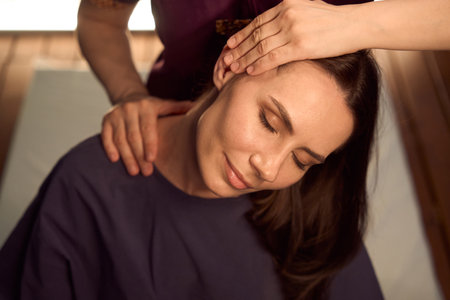 Massotherapist stretching patient cervical spine muscles in seated positionの写真素材