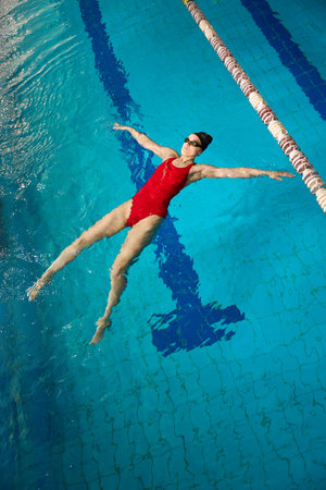 Experienced female athlete doing starfish float in swimming poolの写真素材
