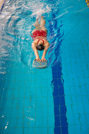 Female athlete in swimsuit practicing flutter kicks in waterの写真素材