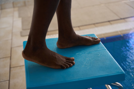 Sportsman getting ready to dive into swimming pool waterの写真素材
