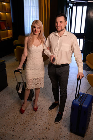 Beautiful couple in love holding suitcases, waiting for hotel check-inの写真素材