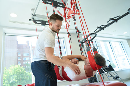 Male undergoing sling exercise therapy with physical therapistの写真素材