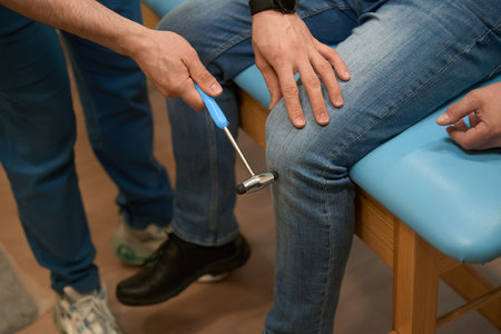 Experienced doctor checking patellar reflex in man during neurological examの写真素材
