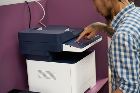 Freelancer with dreadlocks uses a photocopier in a coworking space