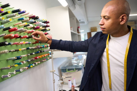 Concentrated clothier choosing tailoring threads in his atelier