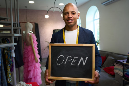 Friendly dressmaker inviting clients to workshop with chalkboard welcome sign