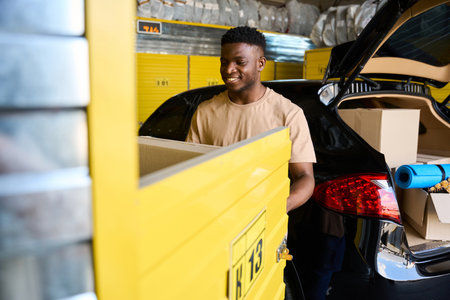 Young man loads a cardboard box with things into yellow cell