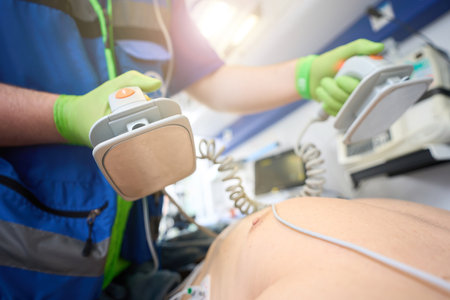 Employee of mobile team with defibrillator electrodes in his handsの写真素材