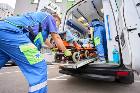 Paramedic in a protective mask unloads a patient from an ambulanceの写真素材