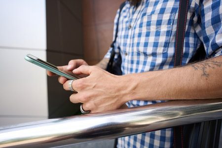 Man in plaid shirt is on phone at modern buildingの写真素材