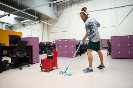 Guy with a headset in his ears cleans office space