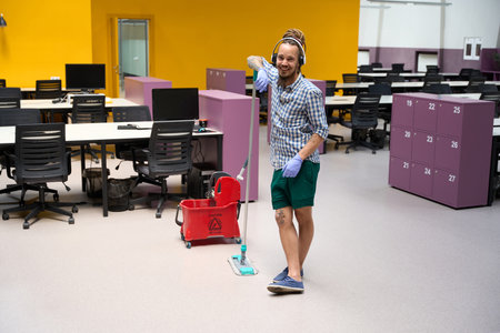 Cheerful cleaner is informal in coworking space with work gadgets