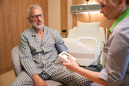 Female medical worker measures the pressure of an elderly man