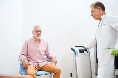 Physiotherapist performs pelvic floor stimulation on an old man