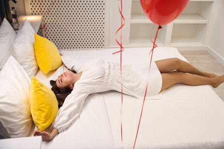 Pretty female dreaming of romantic celebration in contemporary apartmentの写真素材