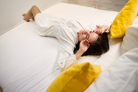 Attractive female relaxing on bed in modern roomの写真素材