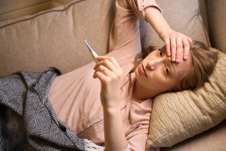 Lady having fever and measuring body temperature
