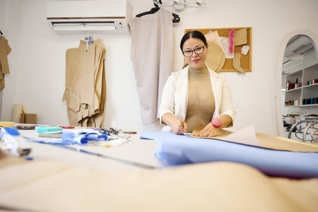 Craftswoman at her workplace cuts blue fabric