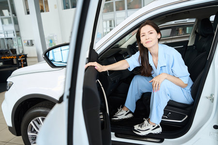 Pretty female posing at camera in car dealershipの写真素材