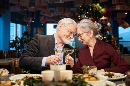 Happy aged man and woman with glasses of champagne celebrating New Year Eveの写真素材