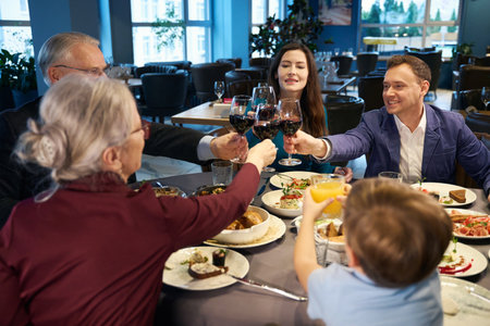 Happy family holding glasses with wine while celebrating Christmasの写真素材