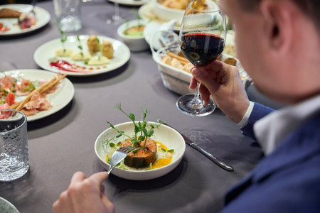 Unrecognizable man holding glass of wine having dinner in restaurantの写真素材