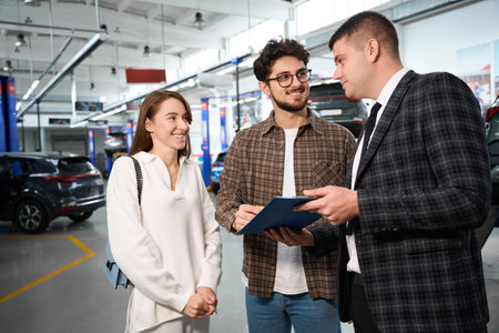 Happy man and woman signing documents buying new automobile in dealership