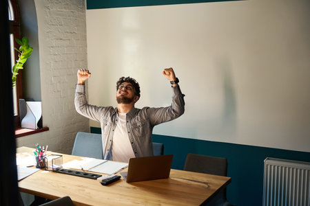 Young excited successful caucasian businessman celebrating win in work