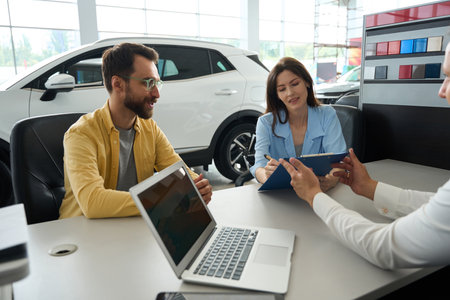 Spouses formalize a deal in office area of car dealershipの写真素材
