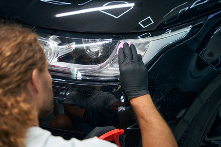 Male is working in a car workshop detailing black carの写真素材